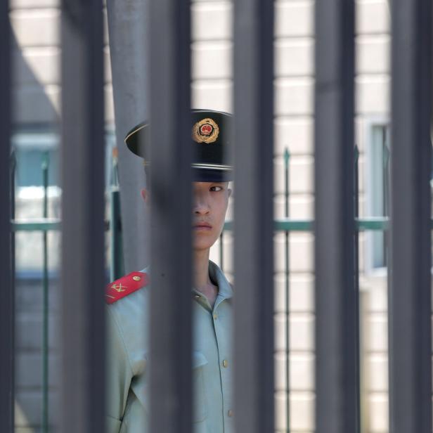 A paramilitary police officer stands guard behind a fence after a blast outside the U.S. embassy in Beijing