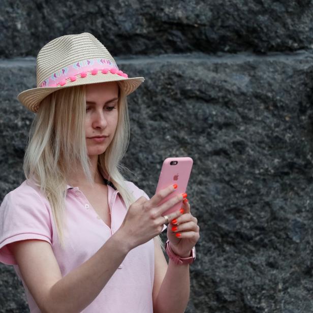 A journalist uses her iPhone as she waits for a news conference in front of the Presidential Administration headquarters in Kiev