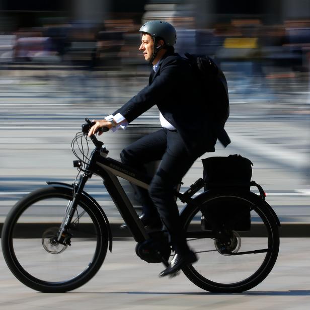 A man rides an electric bicycle, also known as an e-bike, in downtown Milan