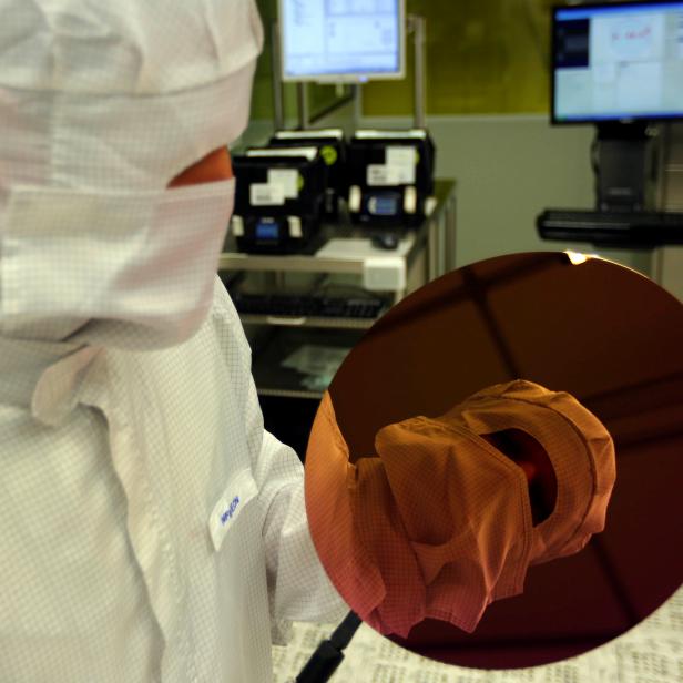 FILE PHOTO: An employee is reflected in a wafer inside a clean room of German semiconductor manufacturer Infineon in Regensburg