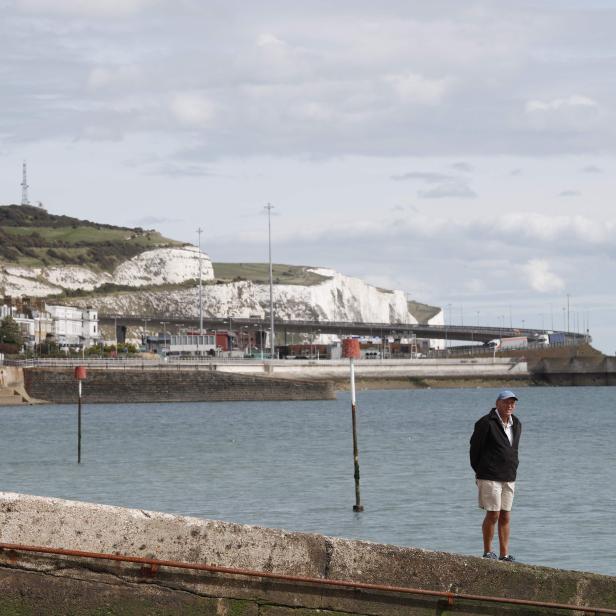 Ein Mann steht an der Küste von Dover vor den Kreidefelsen.