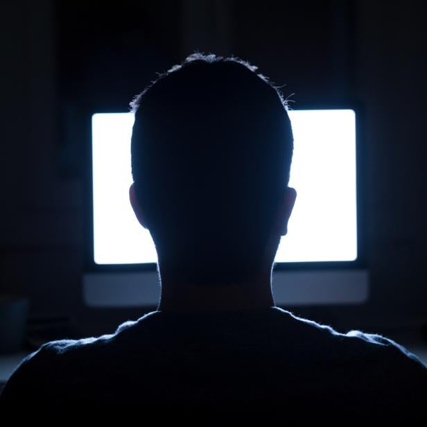 Man seated in front of computer monitor at night