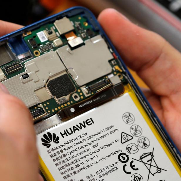 FILE PHOTO: A worker refurbishes a Huawei cell phone at a workshop of the Oxflo company, specialised in refurbishment of broken European smartphones in Lusignac