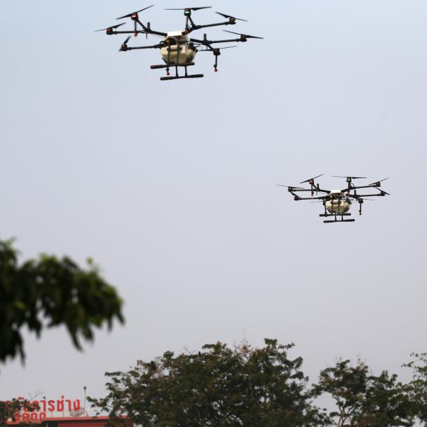 Drones fly and spray water during an operation to reduce air pollution in Bangkok