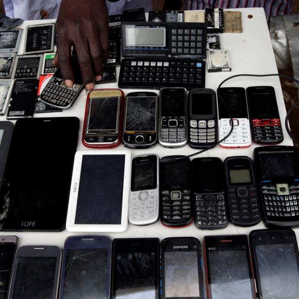 Kennedy Akech arranges used cell phone handsets and batteries on sale at his makeshift market stall within Kibera slum in Nairobi