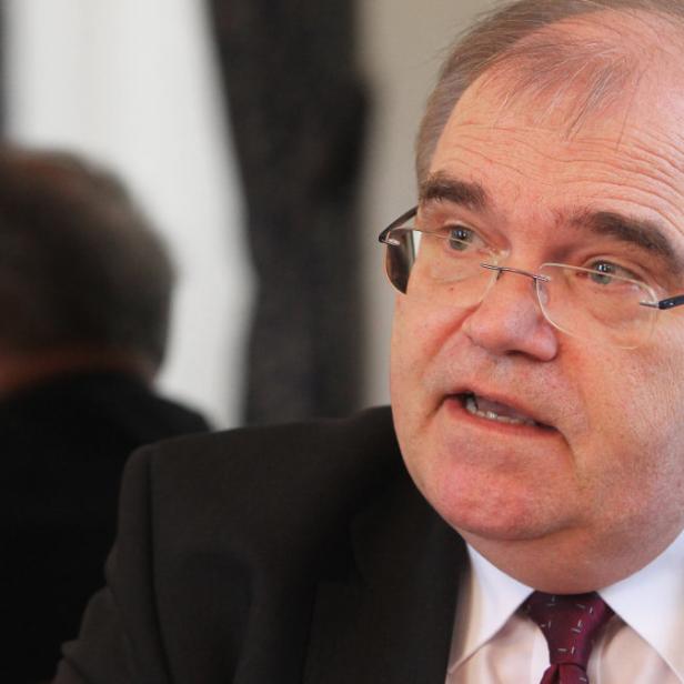 Ein Mann mit Brille und Anzug spricht.