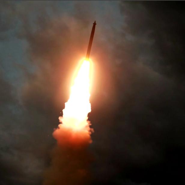 Eine Rakete startet vor dunklem Himmel mit Wolken.