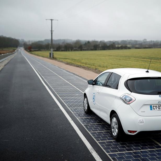 An automobile drives on a solar panel road during its inauguration in Tourouvre