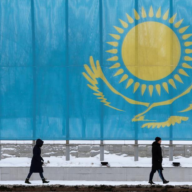 People walk past a gaint Kazakhstan's flag in Astana