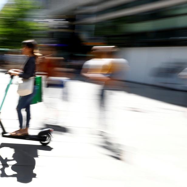 A young woman rides an e-scooter through a pedestrian area in Frankfurt