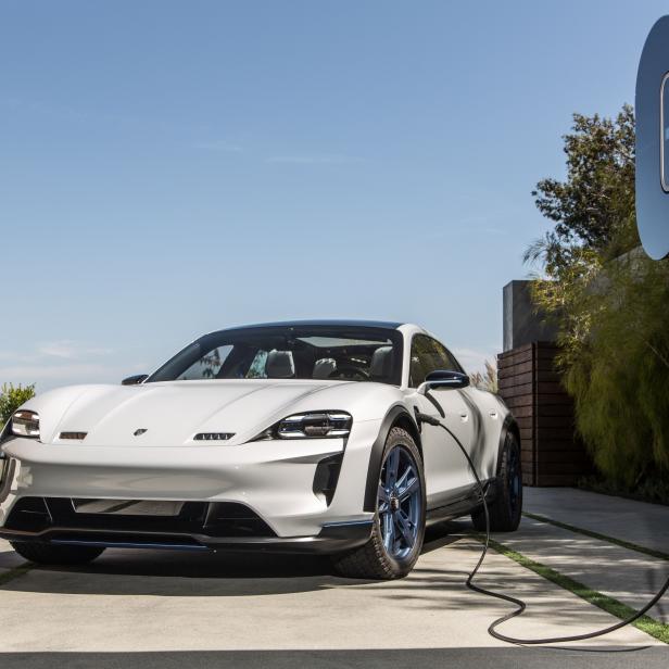 Ein weißer Porsche Taycan wird an einer Ladestation im Freien aufgeladen.