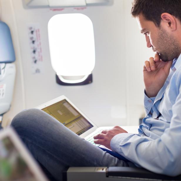 Businessman working with laptop on airplane.