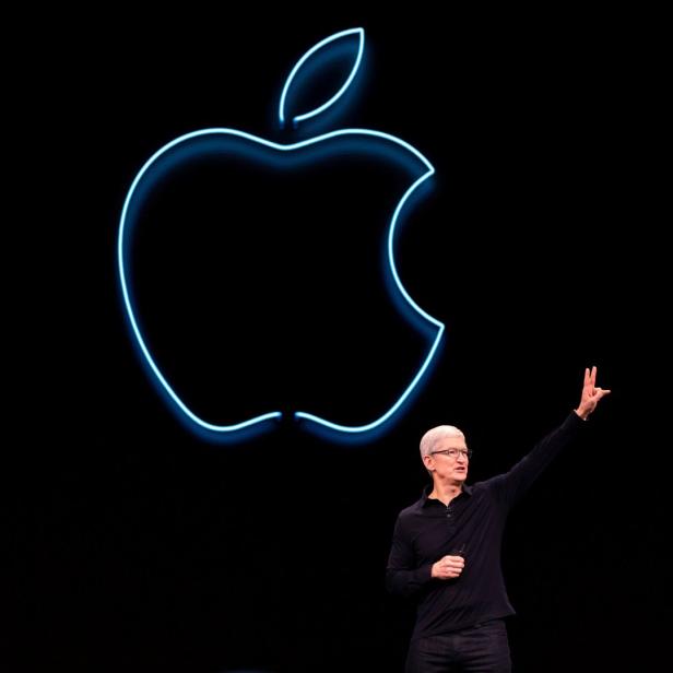 Tim Cook präsentiert vor einem leuchtenden Apple-Logo.