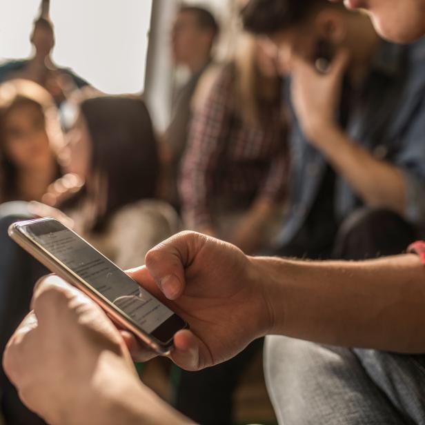 Close up of unrecognizable student using cell phone on a break in the classroom.