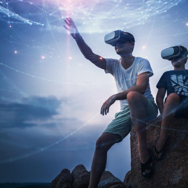 Father and son using Virtual Reality glasses sitting outside