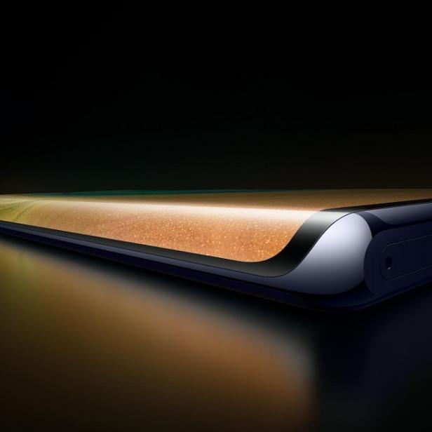 Nahaufnahme eines modernen Smartphones mit abgerundeten Kanten auf einer dunklen Oberfläche.