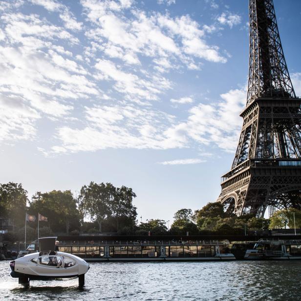 Ein weißes Tragflächenboot fährt auf der Seine mit dem Eiffelturm im Hintergrund.