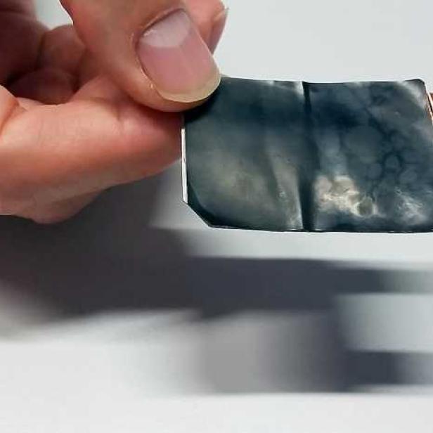 Eine Hand hält eine flexible Batterie mit Kupferkontakten.