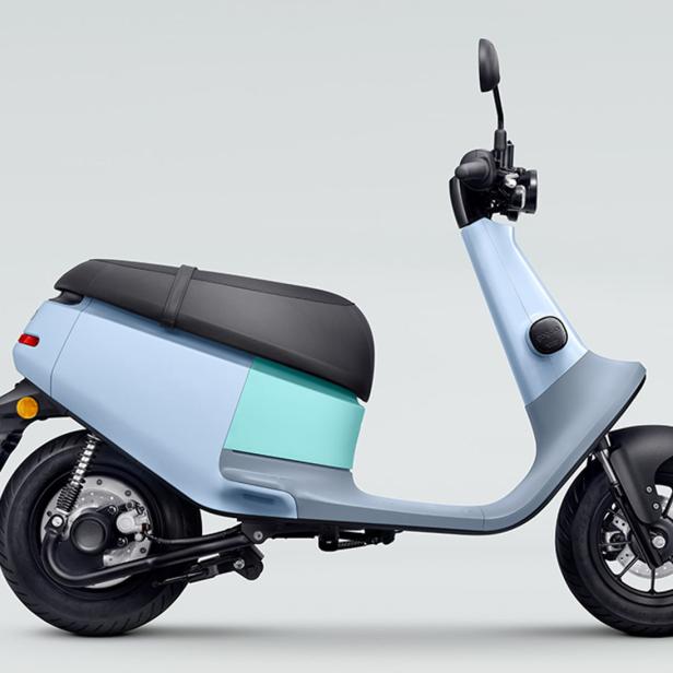 Ein hellblaues und graues Elektroroller-Moped steht auf einem grauen Hintergrund.