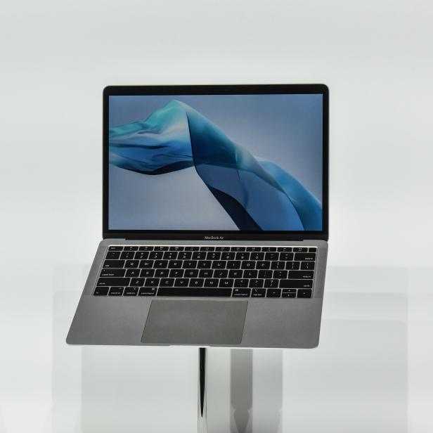 Ein MacBook Air steht auf einem Tisch vor einem weißen Hintergrund.