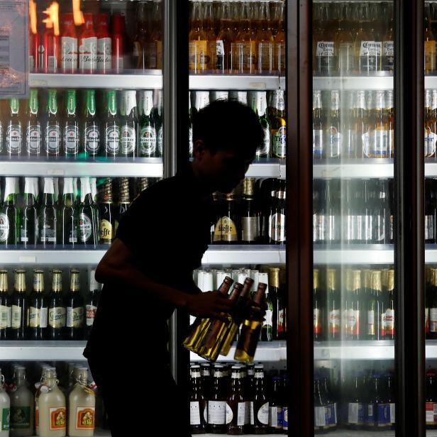 A man takes bottles of tiger beer out of a beer fridge at a restaurant in Hanoi