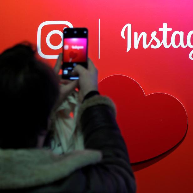 FILE PHOTO: A visitor takes a picture of the Instagram application logo at the Young Entrepreneurs fair in Paris