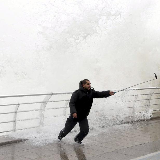 File photo of a man taking a selfie by a crashing wave on Beirut's Corniche, a seaside promenade, as high winds sweep through Lebanon during a storm