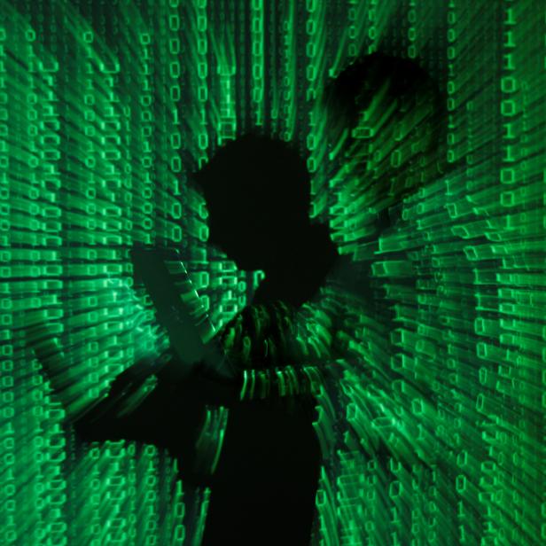 FILE PHOTO: An illustration picture shows projection of binary code on man holding aptop computer in Warsaw