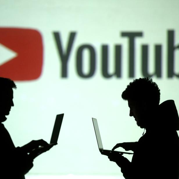 FILE PHOTO: Silhouettes of mobile device users are seen next to a screen projection of Youtube logo in this picture illustration