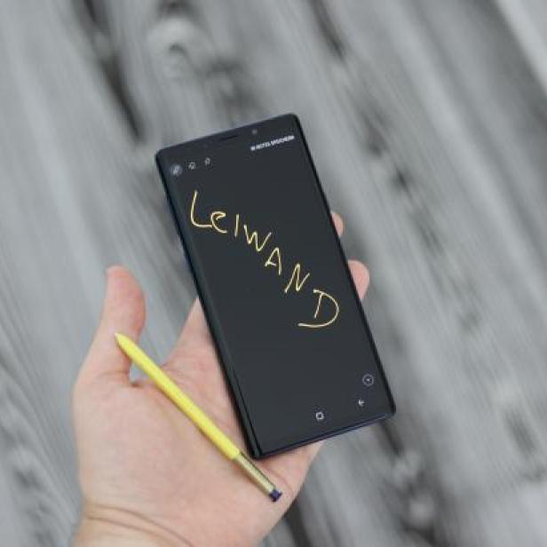 Eine Hand hält ein Smartphone, auf dessen Bildschirm mit einem Stift das Wort „Leiwand“ geschrieben steht.