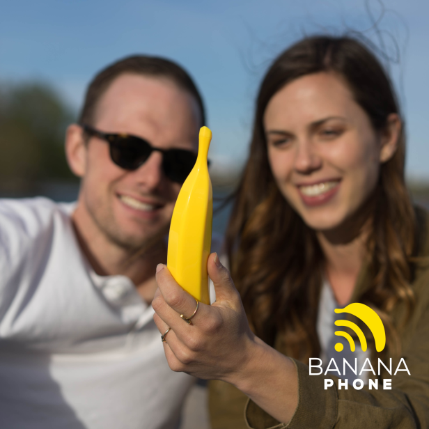 Ein Mann und eine Frau betrachten lächelnd ein gelbes Bananentelefon.