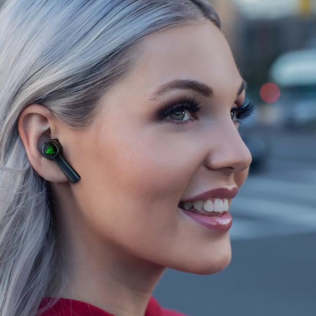 Eine Frau mit blonden Haaren trägt einen schwarzen kabellosen Kopfhörer von Razer.