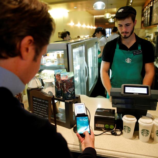 Man uses iPhone 7 smartphone to demonstrate mobile payment service Apple Pay at cafe in Moscow