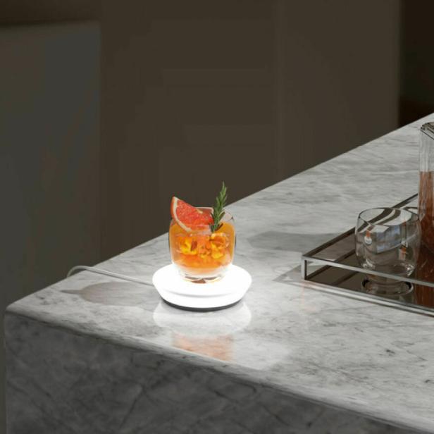 Ein Cocktail mit Grapefruit und Rosmarin steht auf einem beleuchteten Untersetzer.