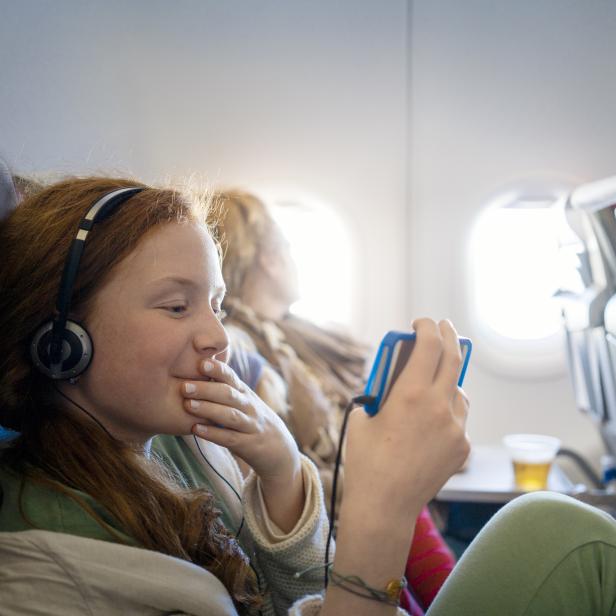 Girl on an airplane watching a movie on a mobile phone