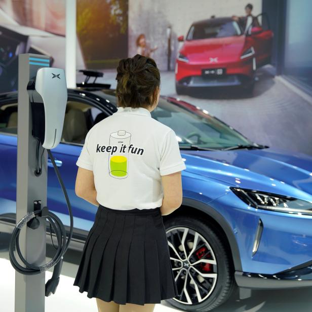 Staff member of Xpeng Motors stands next to the charging station at the company's booth during the media day for Shanghai auto show