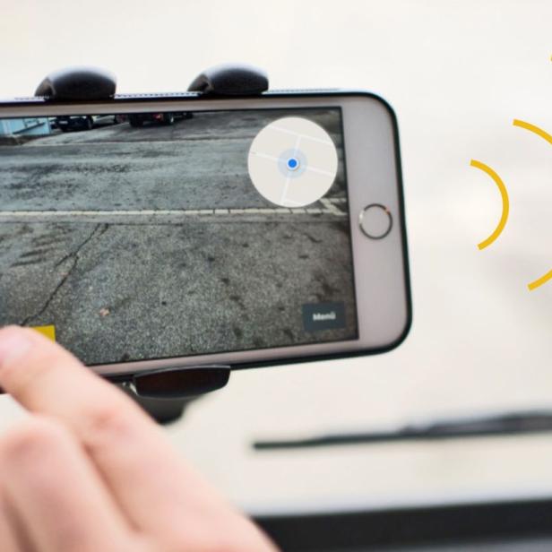 Ein Smartphone in einer Halterung zeigt eine Straßenansicht mit Navigationsdaten.