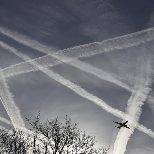A passenger plane flies through aircraft contrails in the skies near Heathrow Airport in west London