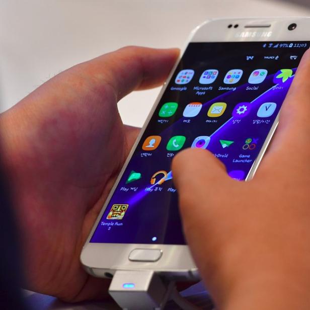 Eine Person bedient ein Samsung-Smartphone mit verschiedenen Apps auf dem Bildschirm.