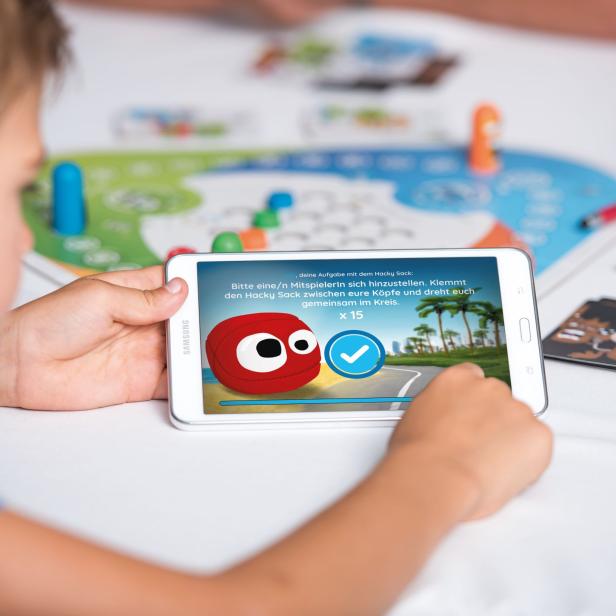 Ein Kind spielt ein Spiel mit einem Hacky Sack auf einem Tablet.