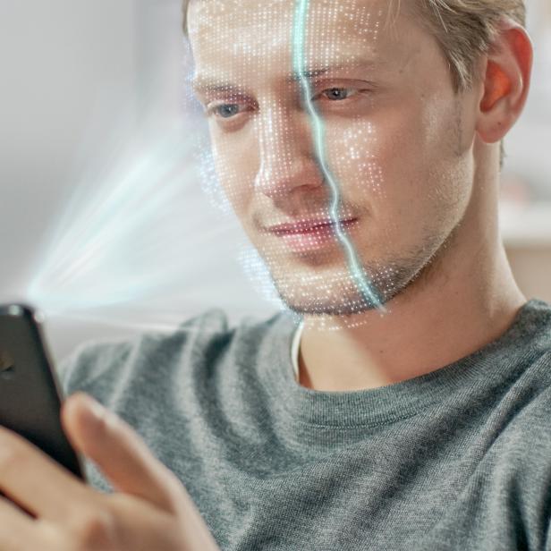 Young Man Identified by Biometric Facial Recognition Scanning Process from His Smartphone. Futuristic Concept: Projector Identifies Individual by Illuminating Face by Dots and Scanning with Laser