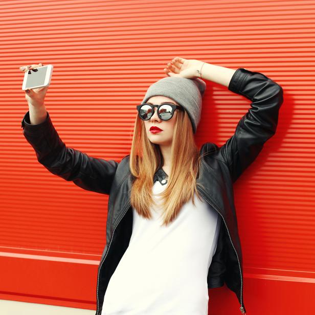 Fashion hipster cool girl taking self-portrait on smartphone in