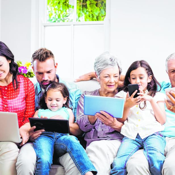 Family using technologies while sitting in sofa