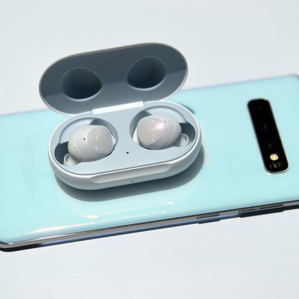 Ein Paar Samsung Galaxy Buds in einem offenen Ladeetui, das auf einem Smartphone liegt.