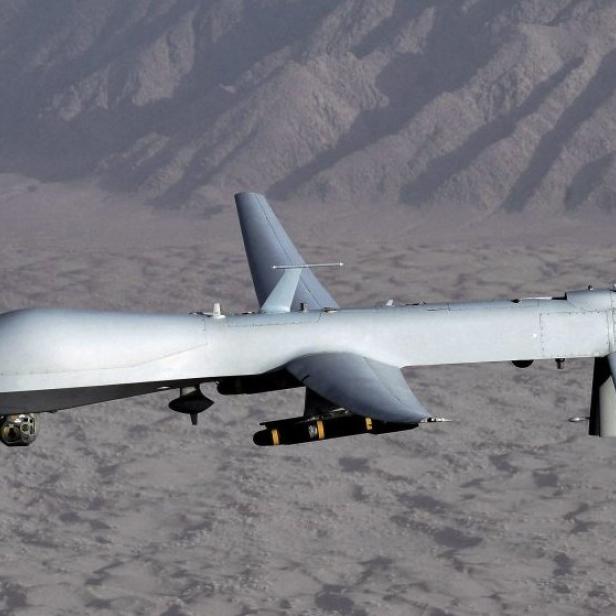 Eine unbemannte MQ-9 Reaper Drohne im Flug über einer Wüstenlandschaft.