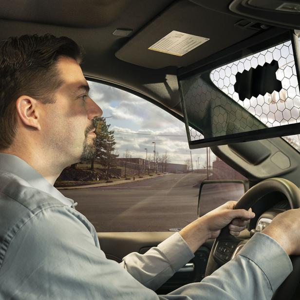 Ein Mann fährt ein Auto mit einem digitalen Rückspiegel.