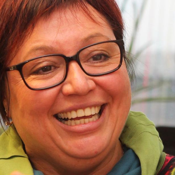 Eine lachende Frau mit Brille und roten Haaren.