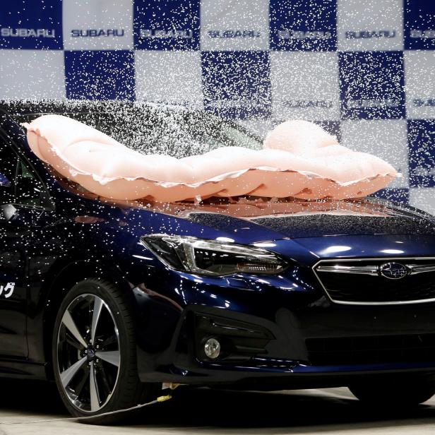 External airbag splashes mock snow, covering the surface of Subaru Impreza G4, as it is triggered during collision test demonstration, at its factory in Ota