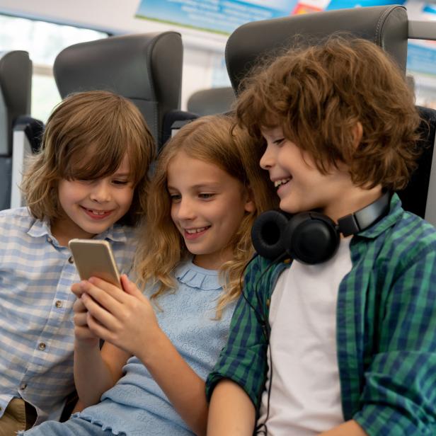 Kids traveling by train and playing on a cell phone