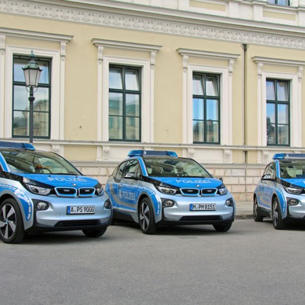 Drei BMW i3 Polizeiautos stehen vor einem Gebäude.